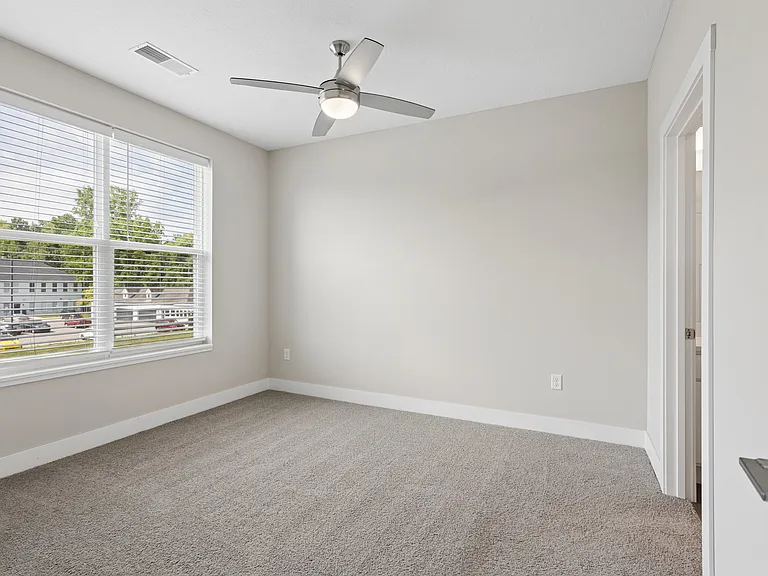 Carpeted bedroom with ceiling fan of a Tiffany Flats apartment home.