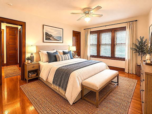 Bedroom with beautiful hardwood floors and a large three bay window.