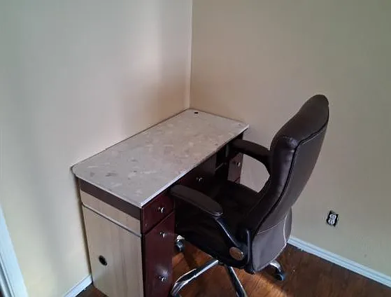 Compact work nook with a built-in desk and rolling office chair, ideal for studying or remote work in a quiet corner.