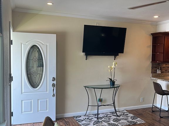 Bright and welcoming entryway with a view of the living area featuring comfortable seating, a smart TV, and modern decor. Perfect for relaxation and entertainment.
