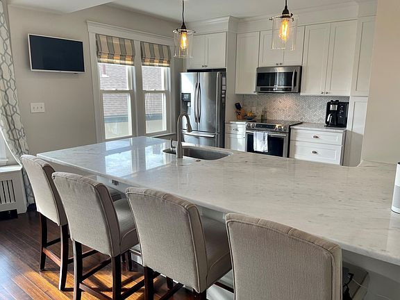 Massive island that separates the kitchen and dining space. The mounted TV stays for you to enjoy.