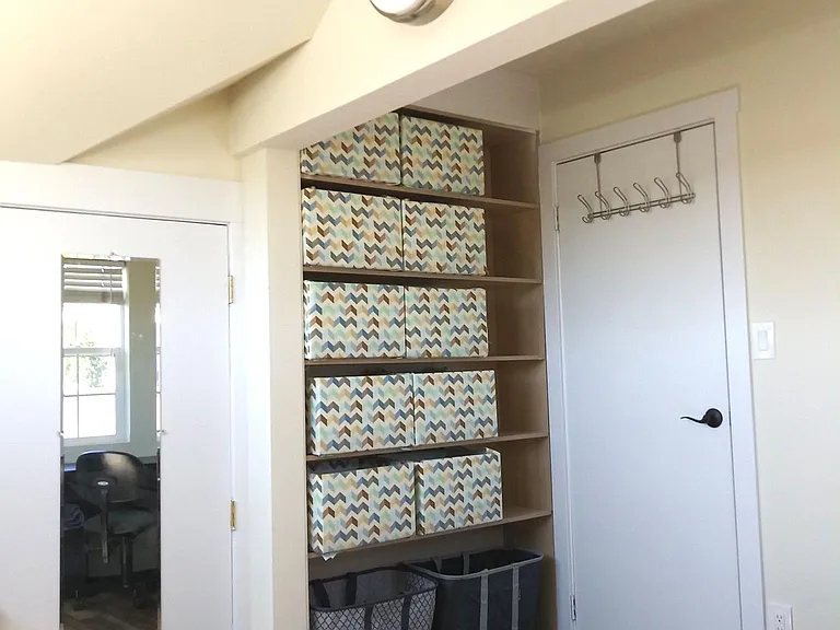 Door to living room showing storage shelves. (sized for standard hampers and bankers boxes)