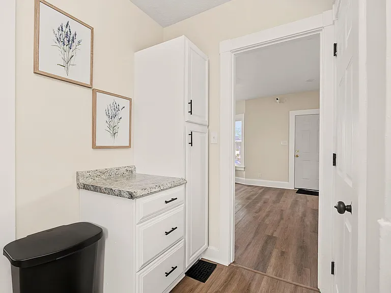 Transitional hallway area with built-in white cabinetry and granite counter space for extra storage and prep.