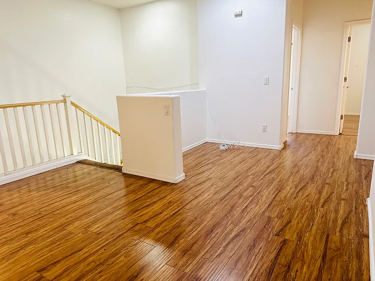 Spacious upstairs loft with wood-look flooring, ideal for a second living area, media room, or study space.