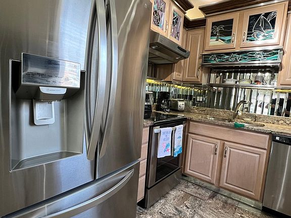 Stainless French door refrigerator. Floor is granite matching countertop. Backsplash is 3" beveled mirror Cabinets have custom backlit stained glass panels.