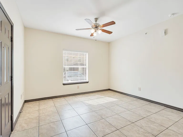 Spacious empty room with tile flooring and a ceiling fan, part of the La Joya Apartments in Laredo, Texas