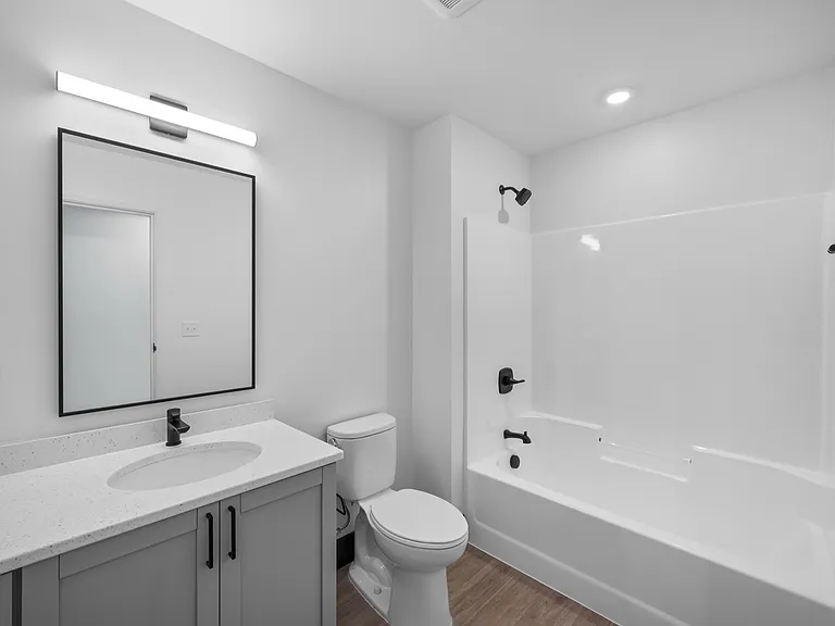 Elegant modern bathroom with sleek fixtures, a large mirror, and a pristine shower-tub combo. Elegant modern bathroom with sleek fixtures, a large mirror, and a pristine shower-tub combo.