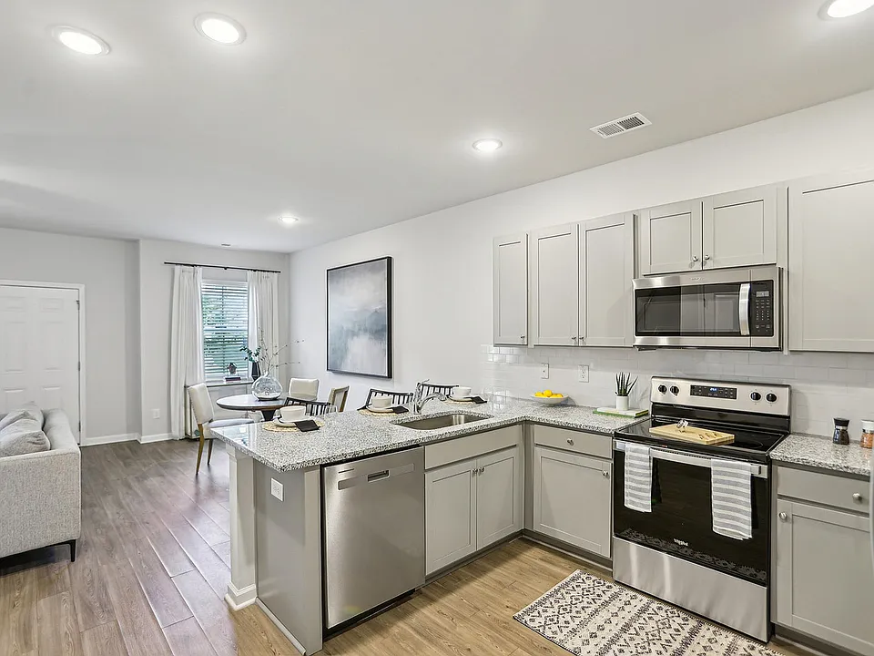 Kitchen with light grey cabinetry, stainless steel appliances and wood style flooring