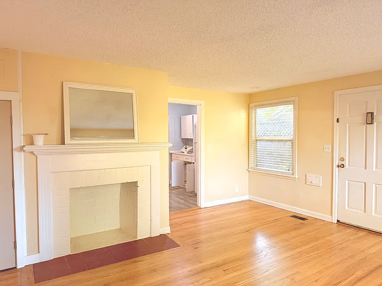 Living room: beautiful wood floors, non-functional fire place leads to kitchen/dining area.