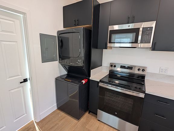 Kitchen with laundry and refrigerator. Electric oven and range with microwave above.