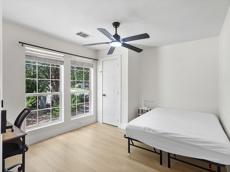 Bedroom with two large windows, ceiling fan, and space for a bed plus a small desk or seating area.