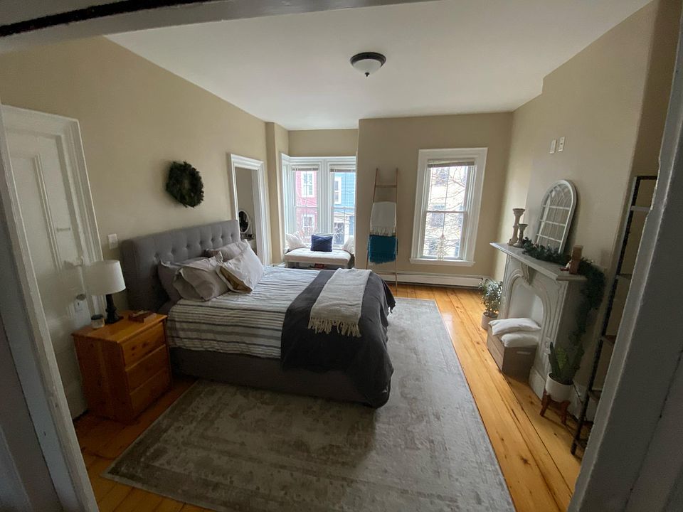 Large light filled bedroom with marble fireplace mantle.