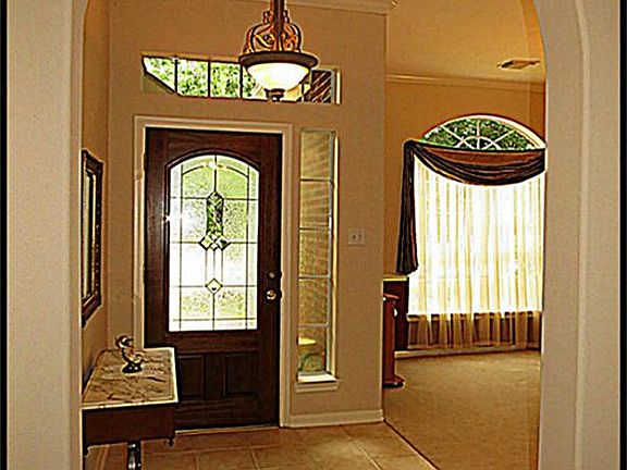 Arched entry way with tile and lead glass front door.