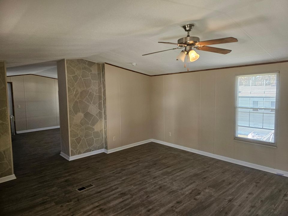Living room has mini blinds and ceiling fan.