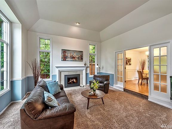 Plenty of natural light for this living room featuring oversized windows, gas fireplace and French doors.