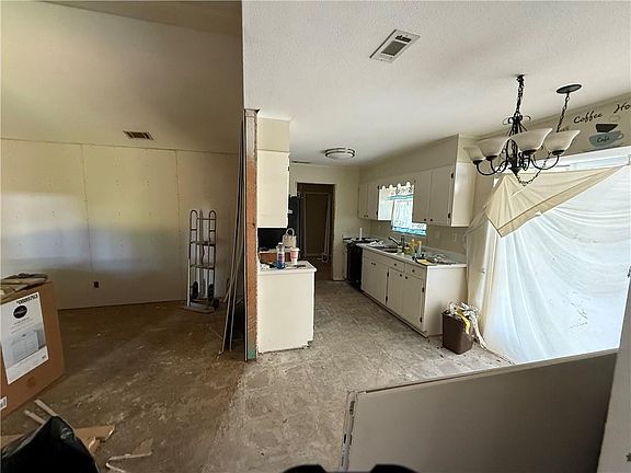 Empty room with light wood finished floors, visible vents, baseboards, and a chandelier