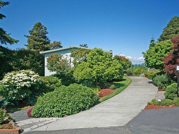 The end of the house with driveway & gardens.