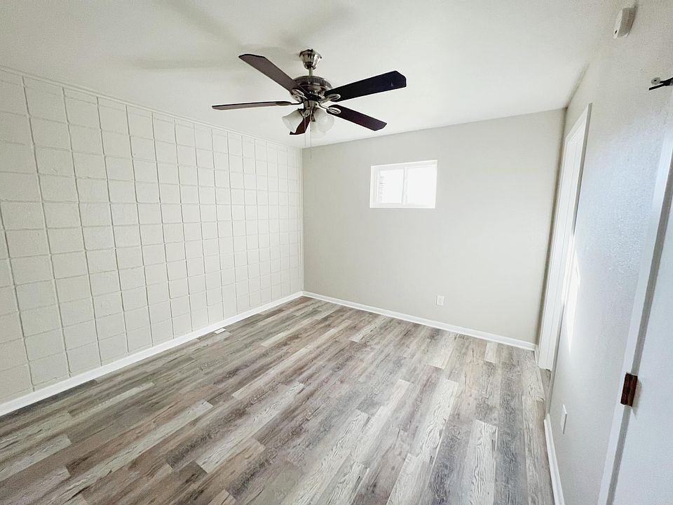 The bedroom boasts newly installed luxury vinyl plank flooring, a ceiling fan for added comfort, and white shiplap accent walls for a fresh, contemporary look.