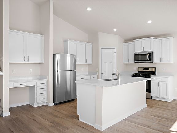 The kitchen has stainless steel appliances and plank flooring.
