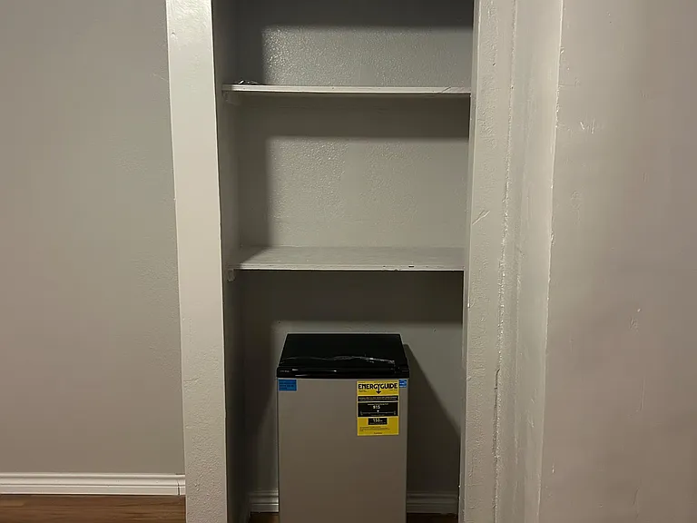 Built-in shelving nook provides convenient storage, with space for a compact fridge or personal items nearby.