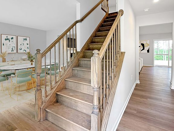 View from foyer with wood staircase, luxury vinyl plank flooring, and sightlines into dining and liv