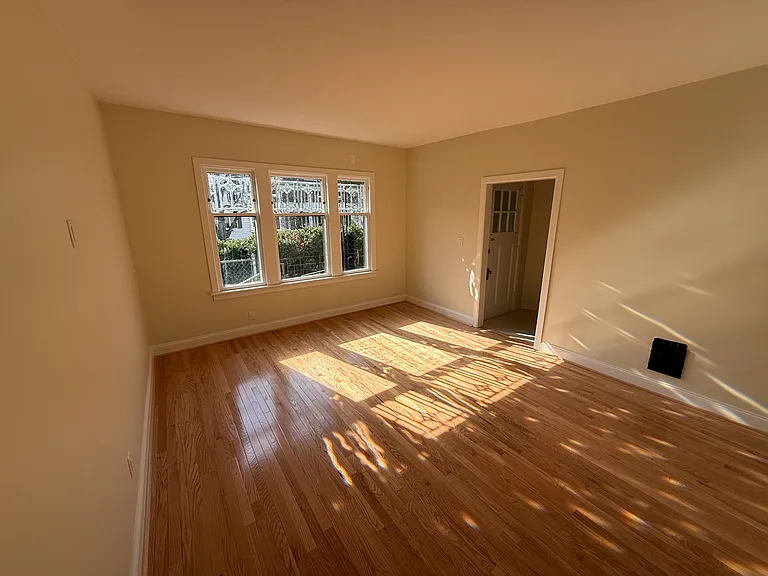 Sunny wide open living room with lovely leaded glass windows that flood the room with light. Brand new solid wood floors.