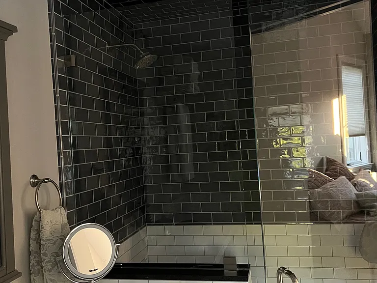 Bathroom view showing shower with glazed brick walls, designer-quality shower head, and glass wall to maximize natural light.