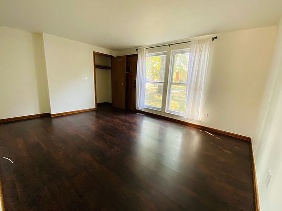 Living room with tons of light, looking out to sitting area and green space. Coat closet.