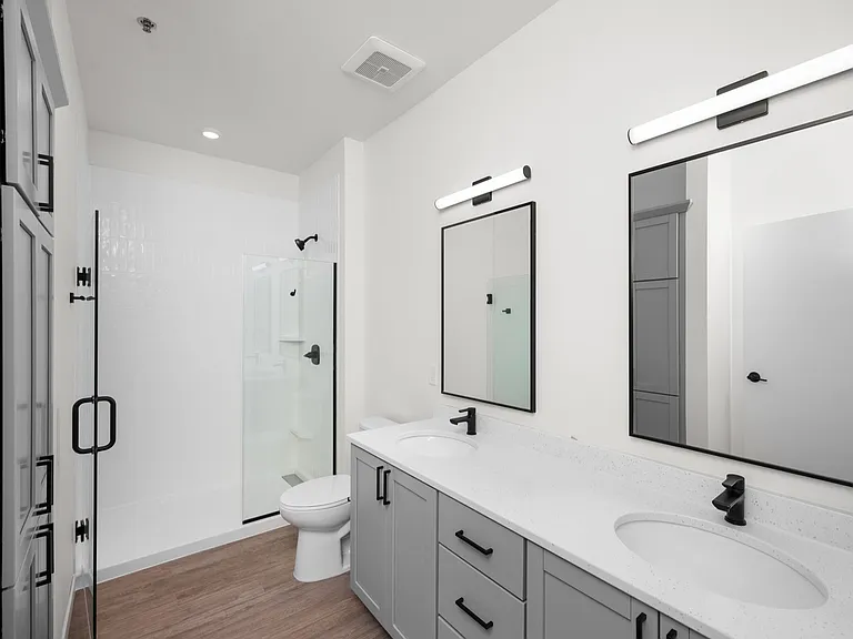 Sleek modern bathroom with dual sinks, elegant mirrors, and a spacious glass shower. Sleek modern bathroom with dual sinks, elegant mirrors, and a spacious glass shower.
