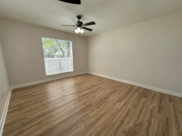 Bright and spacious room with elegant wood-style flooring, large window, and ceiling fan, perfect for comfortable living. Bright and spacious room with elegant wood-style flooring, large window, and ceiling fan, perfect for comfortable living.