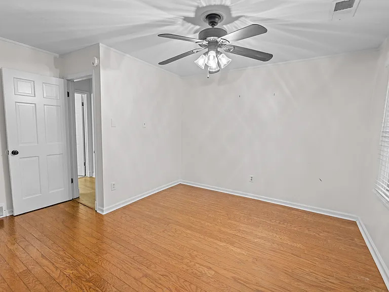 Bright, move-in ready bedroom with gleaming hardwood floors, ceiling fan, and closet access _ comfortable and versatile.
