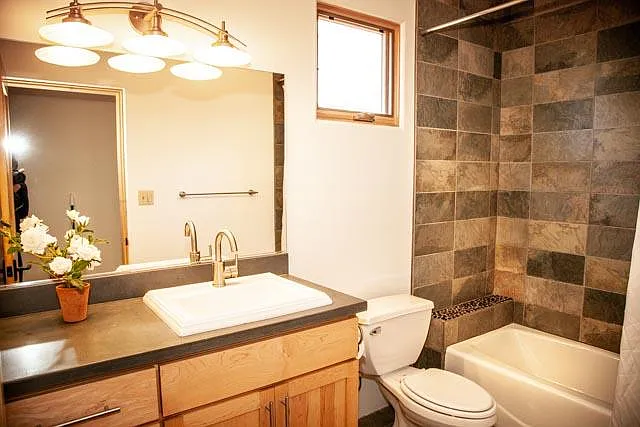Guest bath features upscale tile and stone tub/shower, designer surfaces and high-end sink and finishes.