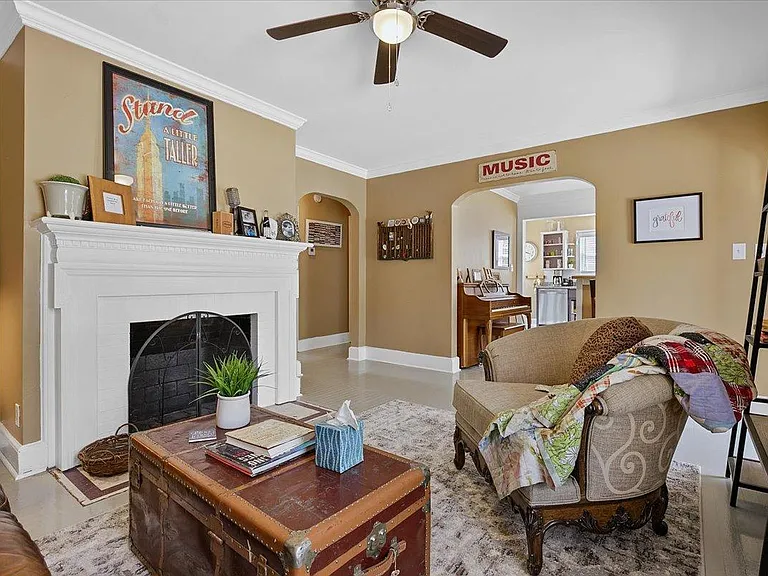 Cozy living room at Hunsucker's Place near Downtown Greensboro, featuring a comfortable leather couch, a functional writing desk, and an open-concept design connecting to the dining room with a piano and the fully equipped kitchen_perfect for relaxation