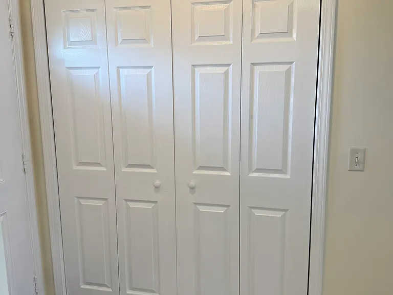 Laundry closet doors to access washer and dryer. Area located next to main door entrance.