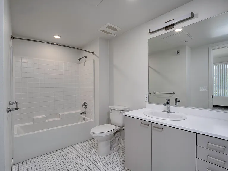 Bathroom A with a spacious vanity, bright lighting, and a full-size tub and shower.