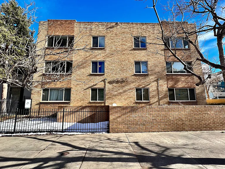 Charming three-story brick apartment building with large windows and a secure gated entrance, offering a welcoming and safe living environment.