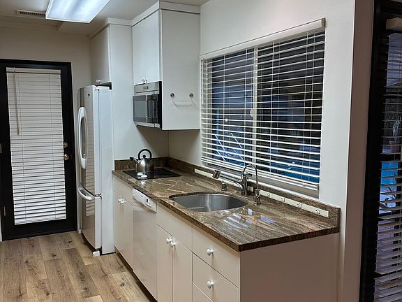 Kitchen with dishwasher, fridge, electric stovetop and microwave/convection unit.