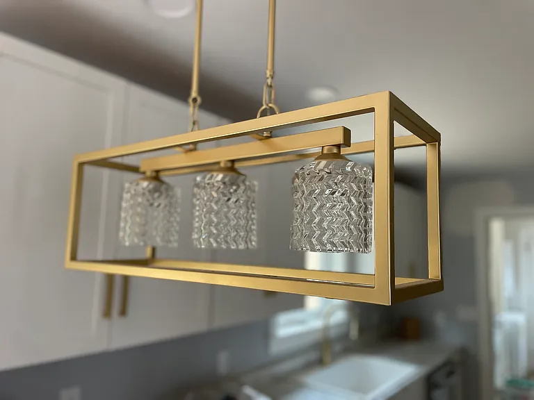 Modern gold lighting above kitchen bar.