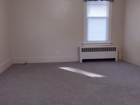 Newly carpeted living room with high ceilings, ceiling fan, mini-blinds and valances.