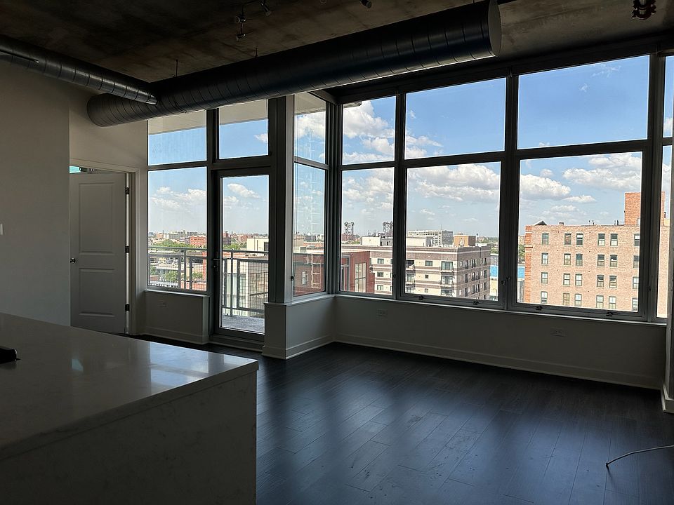 Open-concept living room with 10 ft. ceilings, oversized windows, and sweeping views of the city