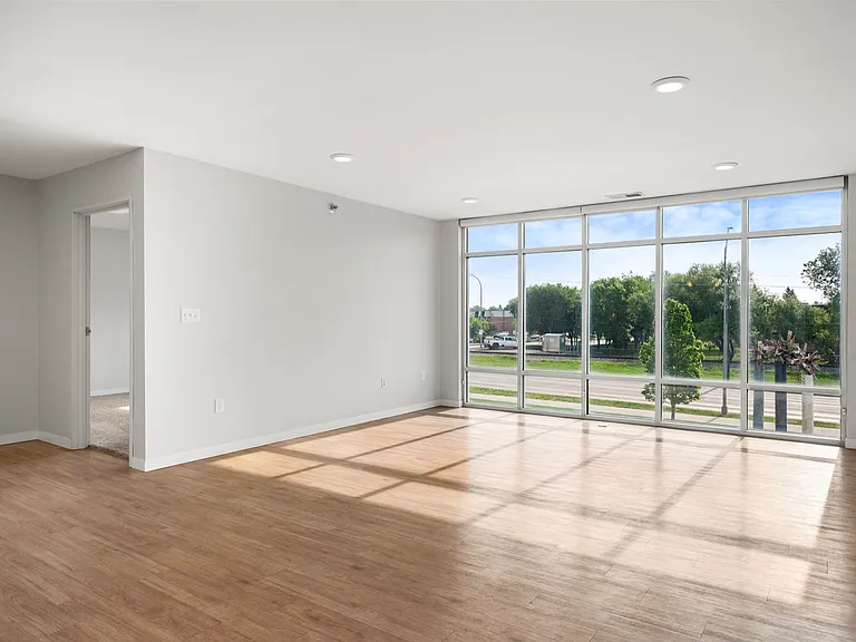 Bright and spacious living area with floor-to-ceiling windows, elegant wood flooring, and a view of lush greenery. Bright and spacious living area with floor-to-ceiling windows, elegant wood flooring, and a view of lush greenery.