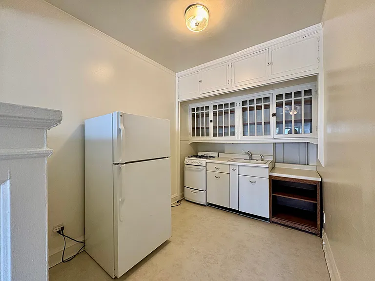 Charming vintage kitchen featuring classic white cabinetry, a spacious fridge, and cozy lighting. Charming vintage kitchen featuring classic white cabinetry, a spacious fridge, and cozy lighting.