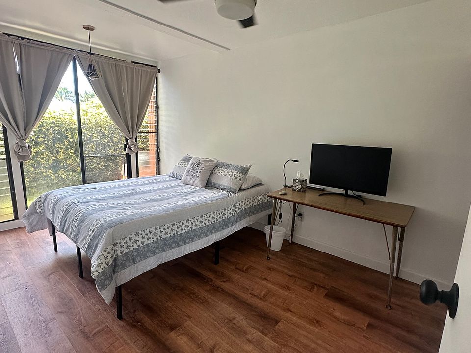 Bedroom 2 with Window AC, Ceiling Fan, and Mirrored Glass Sliding Door Closets.