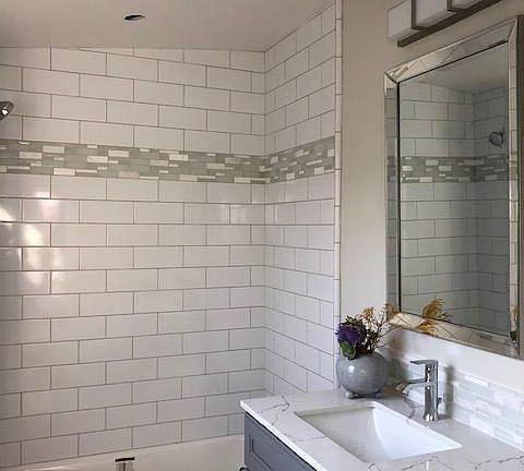 Beautiful bath with natural light. Tub/shower with white subway tile, glass/marble accents, gray maple shaker vanity, quartz counter, LED lighting, tile floors.