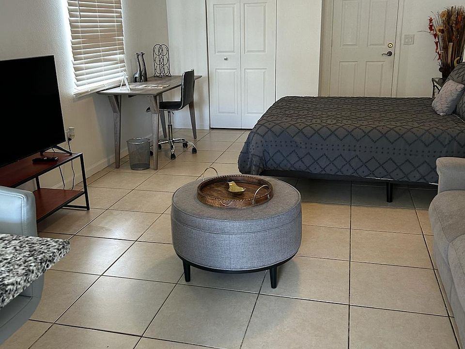 Studio with pouf, workspace, and Smart TV for comfort and entertainment.