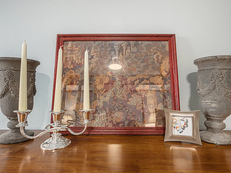 Elegant cabinet displays decorative candles, artwork, and vases, adding charm and a cozy, curated touch to the bedroom.