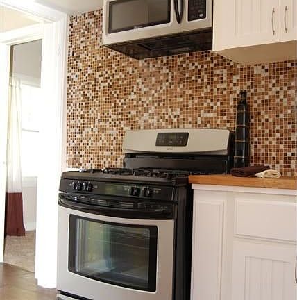 Remodeled kitchen showing new gas range, new microwave, & glass tile bk splash