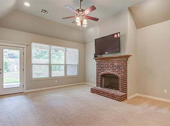 Living room with vaulted ceiling, gas fire place, door to back covered patio, and blinds that adorn the large windows!