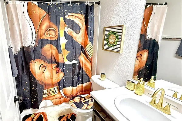 This second-floor full bathroom boasts a clean & modern white interior, creating a bright atmosphere. It features a spacious bathtub, an overhead shower, a sleek sink, and a toilet, along with a functional cabinet for storage.