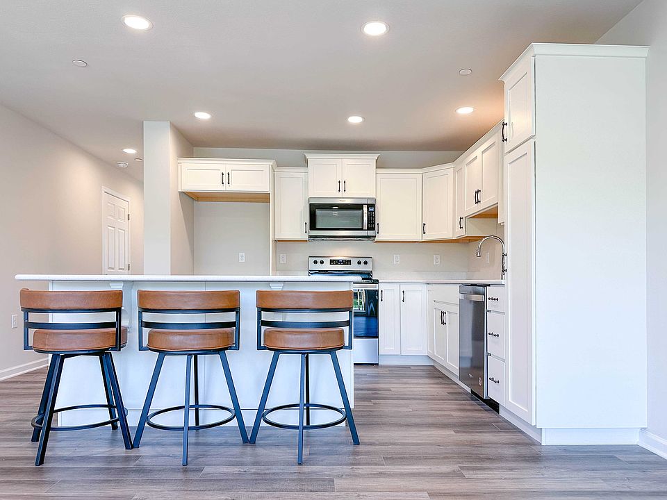 Kitchen with white cabinets and center island with bar overhang